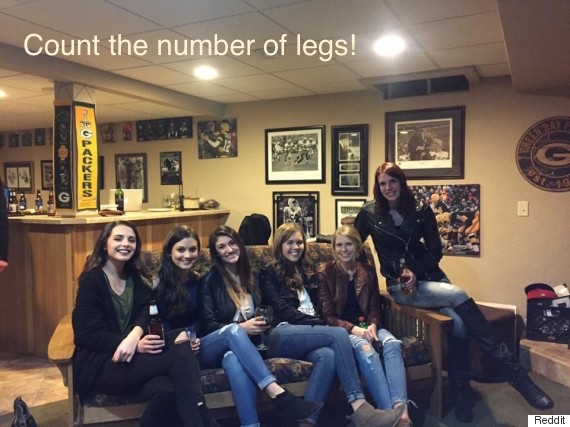 Five women sitting on a sofa in such a way that only four pairs of legs are noticeable.